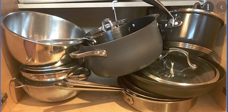 messy kitchen cabinet with pots on the top of each other